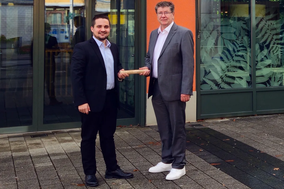 Zwei Männer stehen vor dem Eingang der Bank BSU in Dübendorf und halten sich an einem Stab.